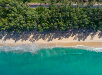 Aerial view of road in beautiful green forest with wave crushing beach and sea, topview from drone.