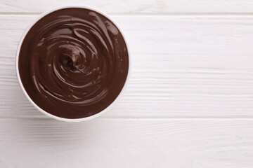 Bowl with tasty chocolate paste on white wooden table, top view. Space for text