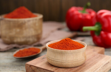 Bowl with aromatic paprika powder on wooden table