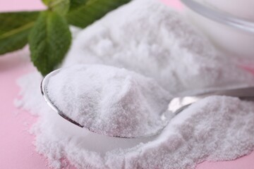 Fototapeta na wymiar Sweet powdered fructose, spoon and mint leaves on pink background, closeup