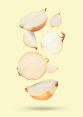 Cut fresh onions falling on beige background