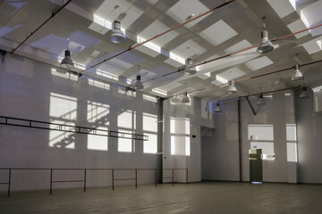 Interior of a large empty space with sun light dropping on the walls