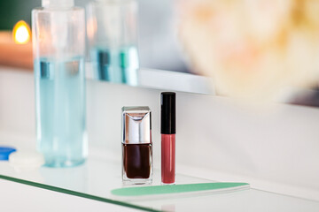 hygiene, beauty and daily routine concept - close up of lotion, nail polish, file and lipstick on mirror shelf in bathroom