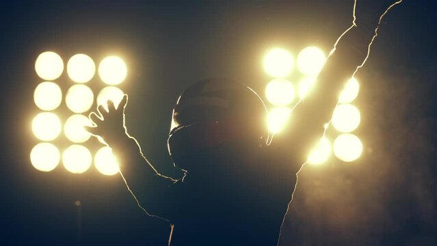 Silhouette of race car driver celebrating the win in a race against bright stadium lights. 100 FPS slow motion shot
