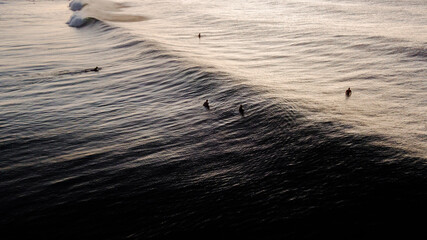 Waves at sunrise and surfers waiting to catch a wave
