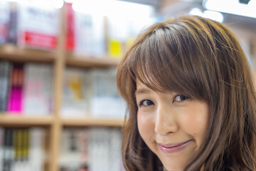 Confident asian woman choosing a book in the library