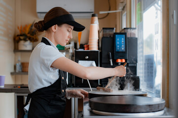 Portrait woman chef baking pancakes in an apron uniform. Fast food service of the city. fast food restaurant is a small business.