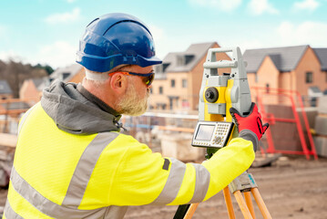 Surveyor builder site engineer with theodolite total station at construction site outdoors during...