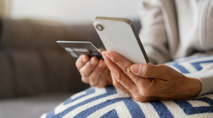 close up senior woman hand hold smartphone to checking on shopping application and using credit card to make purchase for technology and lifestyle concept
