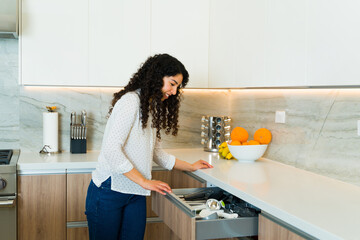 Cheerful young woman preparing to cook opening the kitchen drawer