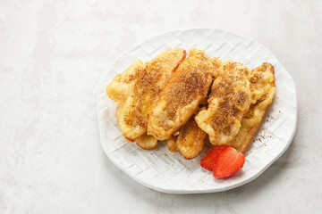 Pisang Goreng or banana fritters with a sprinkling of palm sugar served in white plate. Indonesian food
