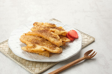 Pisang Goreng or banana fritters with a sprinkling of palm sugar served in white plate. Indonesian food
