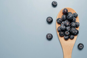 blueberries in a wooden spoon on a blue background. view from above. blueberry flat