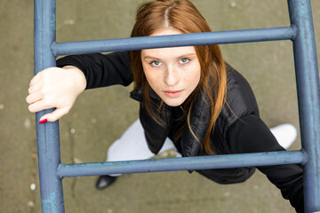 Young woman in black jacket and jeans on playground urban fashion