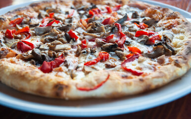 Closeup of fresh pizza on a white plate on a wooden table.