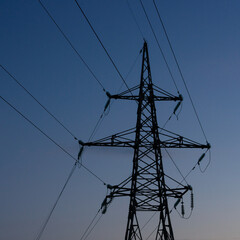 High voltage electric tower silhouette at sunset time and sky on background.