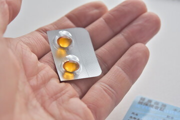 カプセルの薬を手に持っている（健康保険証あり）