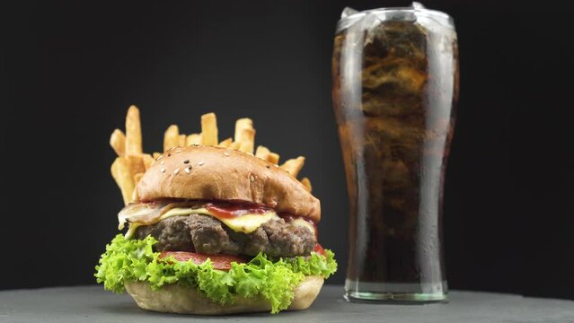 American combo, tasty beef burger with crispy french fries and cold cola on wooden rotating plate