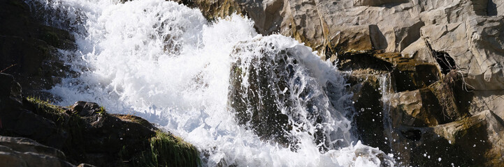 Wild mountain river with small waterfalls flowing through stones