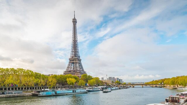 A time lapse of the Eiffel Tower along the river Seine with flyboats passing. Sunny but cloudy autumn day with golden yellow leaves,paris city riverside bay view bridge. Eiffel tower in Paris, France.