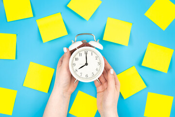White alarm clock and yellow paper reminder,coming soon. Blank yellow sticky notes on a blue...