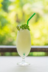 iced lemonade smoothie cocktail in glass cup or lemon water cold blended with parsley leaves on top and green straw for summer fresh drink to fruit sour taste beverage or freshness juice in restaurant