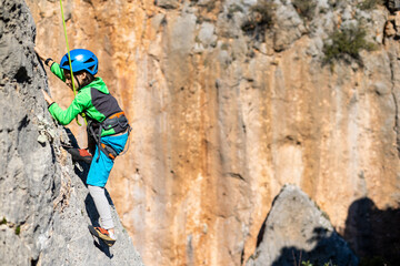 Child rock climber. The boy climbs the rock. The child is engaged in rock climbing on natural...
