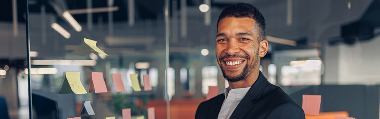 Portrait of smiling african businessman standing in office with crossing hands