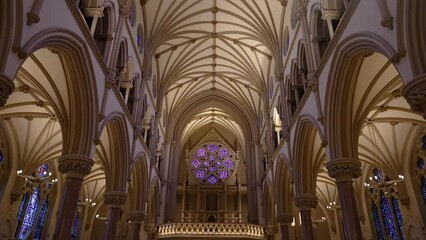 Walking down the middle of a cathedral church aisle looking up at a large stained glass window