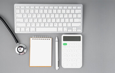 The top view of doctor desk blank notebook and calculator with stethoscope.