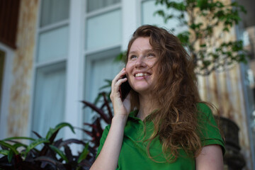 girl uses the phone on the street to call, write a message, the concept of communication, technology at summer