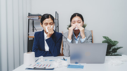 Young pretty asian business woman with friends having covid and sinus in office with sneeze, tissue...