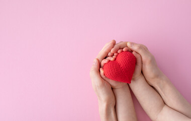 Mother and daughter holding red heart in hands top view. Happy family relationships, love to mom, health care concept.