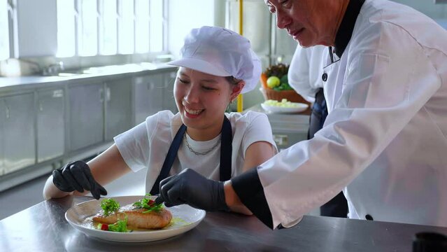 Closeup hands of chef man cooking salmon steak and decoration on plate with professional in kitchen at restaurant, food and garnish for serving, food japan, culinary and recipe with delicious.