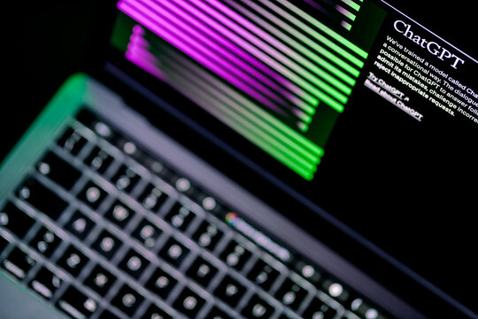 ITALY - March 31, 2023: Laptop screen in focus with Chat Gpt official website. Blurry below, the lit keyboard of the laptop.