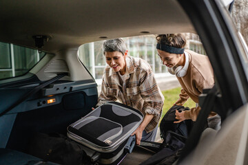 two women mother and daughter pack luggage baggage in trunk of the car © Miljan Živković
