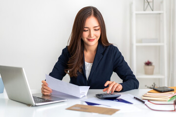 Smiling asian woman using calculator and calculate bills on laptop, paying bill, credit card,...