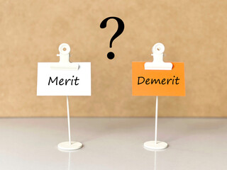 MeritとDemerit文字入り白とオレンジの紙とクエスチョンマーク