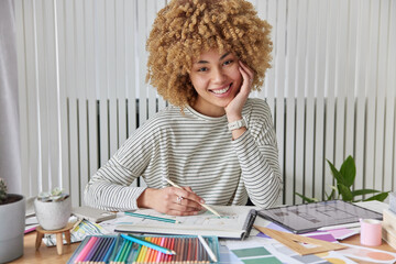 Architecture and interior design concept. Happy curly haired female architect draws sketches for...