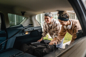 two women mother and daughter pack luggage baggage in trunk of the car