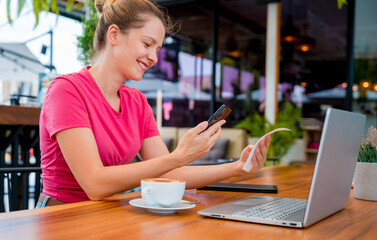 Woman using contactless payment by mobile phone with QR code at cafe