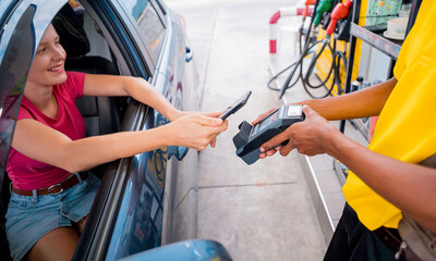 Woman using contactless payment by mobile phone with QR code at car filling station