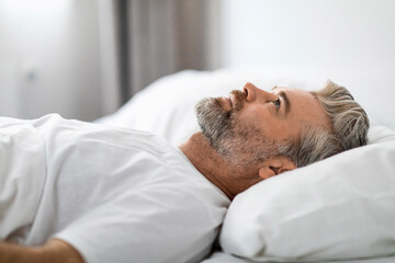 Fototapeta na wymiar Unhappy frustrated middle aged man lying in bed