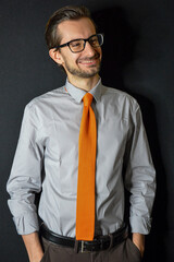 Studio portrait of a businessman with an orange tie and a confident smile. 
