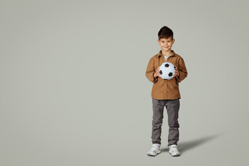 Smiling caucasian 6 years old little boy in casual with soccer ball, enjoy game