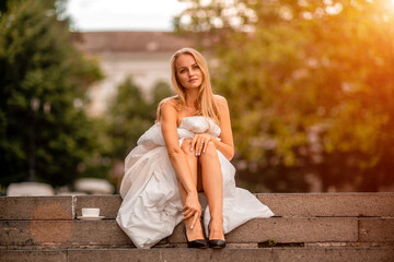 Naklejka premium Woman city blanket. Morning in the big city. A blonde woman in a white blanket is enjoying in the city center. Photographed for social media