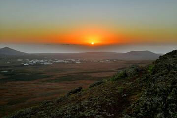 Die Sonne geht über der Kanareninsel Lanzarote auf, und die typischen weißen Häuser stehen in...