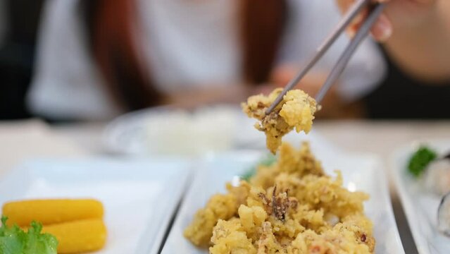 Stainless steel chopsticks holding battered squid tentacles or geso karaage, Japanese food