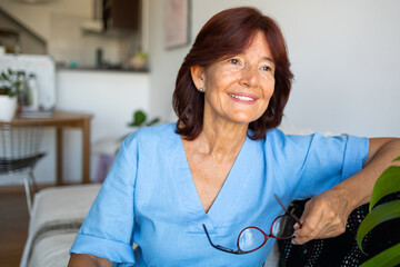 Close up portrait of middle aged latin woman smiling and looking away in the light blue blouse 