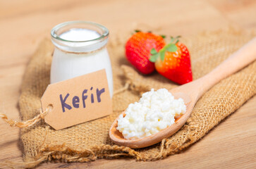 Kefir grains in wooden spoon in front of cups of Kefir Yogurt Parfaits. Kefir is one of the best health foods available providing powerful probiotics. - obrazy, fototapety, plakaty